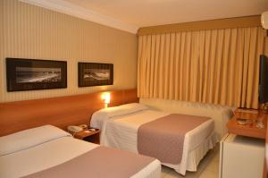 a hotel room with two beds and a television at Arituba Park Hotel in Natal