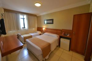 a hotel room with two beds and a desk at Arituba Park Hotel in Natal