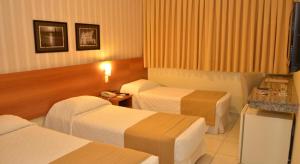 a hotel room with two beds and a television at Arituba Park Hotel in Natal