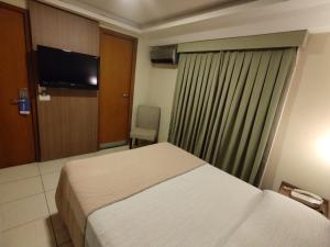 a bedroom with a bed and a window with a television at Arituba Park Hotel in Natal