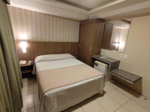 a small bedroom with a bed and a small table at Arituba Park Hotel in Natal