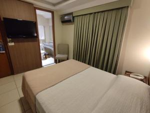 a hotel room with a bed and a television at Arituba Park Hotel in Natal