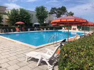 ein Schwimmbecken mit zwei Stühlen und einem Sonnenschirm in der Unterkunft Casa Bugarini in Marcelli