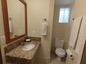 a bathroom with a sink and a toilet and a mirror at Arituba Park Hotel in Natal
