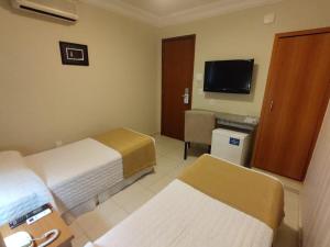 a hotel room with two beds and a television at Arituba Park Hotel in Natal