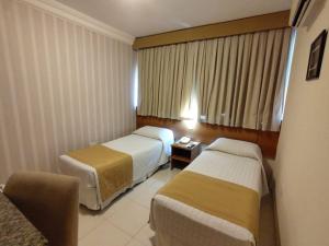 a hotel room with two beds and a chair at Arituba Park Hotel in Natal