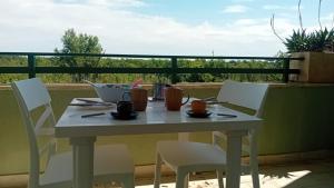 - Balcón con mesa blanca y sillas en Bilocale Delle Robinie in Baia Verde, en Baia Verde