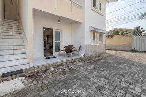a white house with a patio with a table and chairs at Casa c/ piscina e churrasq. Porto S. - BA FLO001 in Coroa Vermelha