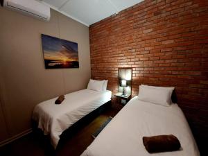 two beds in a room with a brick wall at Fish Eagles Nest in Gariep Dam