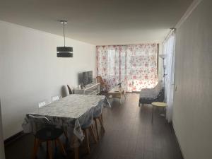 a dining room with a table and chairs and a window at Mar Egeo departamento in Iquique