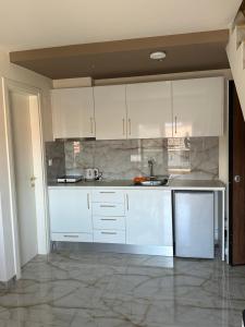 a kitchen with white cabinets and a sink at Malama Rooms in Paralia Katerinis