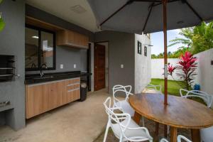 eine Küche mit einem Holztisch und einem Sonnenschirm in der Unterkunft Casa Em Milagres 03 suítes - 300m da Praia in Tatuamunha