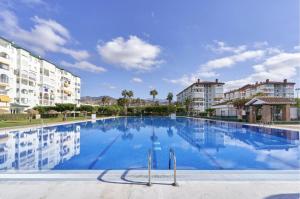 Una gran piscina azul con edificios al fondo. en Apartamento Sugaramanecer, en Torrox Costa