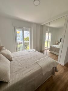 Dormitorio blanco con cama y espejo grande en Apartamento Sugaramanecer, en Torrox Costa