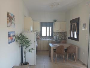 a kitchen with a table and a white refrigerator at Kamares View (Απέραντο Γαλάζιο) in Ayeranós
