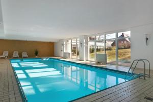 a swimming pool with blue water in a building at Schwarzwaldliebe mit Pool, Sauna in Schonwald im Schwarzwald