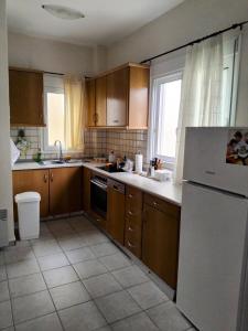 a kitchen with wooden cabinets and a white refrigerator at Spacious apartment Nantia's apartment in Hanioti