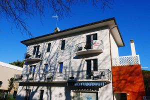 - un bâtiment blanc avec balcon et ciel bleu dans l'établissement Apartments in Bibione 45652, à San Michele al Tagliamento
