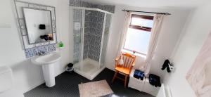 a white bathroom with a shower and a sink at Blue Door Apartment Main St, Carrigart, F92HC04 in Carrigart +16 photos