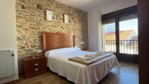Un dormitorio con una cama y una pared de piedra. en Mar de Nubes Piornal 3, en Piornal
