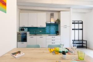 a kitchen with white cabinets and a wooden table at Conca d'Oro Apartments, appartamento 5 e 6 in Arco