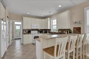 een keuken met witte kasten en een tafel en stoelen bij 3739 Island Drive - Happy Ours in Thomas Landing