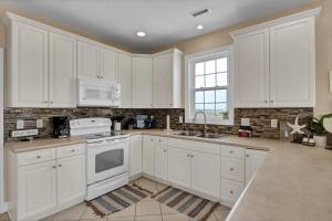 een witte keuken met witte apparatuur en een raam bij 3739 Island Drive - Happy Ours in Thomas Landing