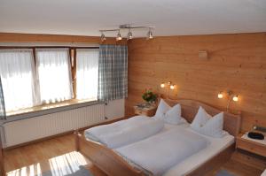 ein Schlafzimmer mit einem Bett und zwei Fenstern in der Unterkunft Gästehaus Klara in Reit im Winkl