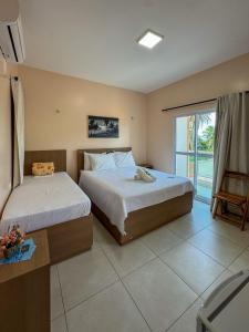 a bedroom with two beds and a balcony at Pousada dos Corais in Mundaú