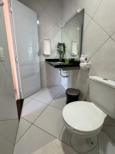 a white bathroom with a toilet and a mirror at Pousada dos Corais in Mundaú +37 photos