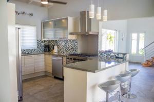 a kitchen with a counter and stools in it at Malmok Beach Break Villa in Palm-Eagle Beach