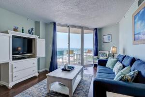 a living room with a blue couch and a tv at St Regis 1405 - Sea of Dreams in North Topsail Beach