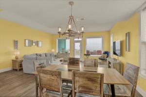 a dining room and living room with a table and chairs at 3974 Island Drive - Suit Up in North Topsail Beach