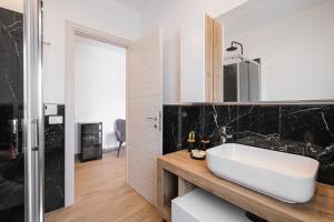 a bathroom with a white sink and black tiles at MaJaMy house in Olbia +54 photos