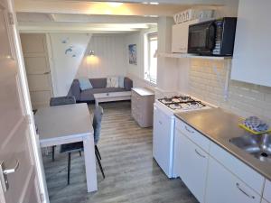 a small kitchen with a stove and a living room at Vakantiewoning met terras vlakbij strand en centrum in Zoutelande