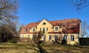 a large yellow house with a red roof at Gutshaus Haidhof in Gingst