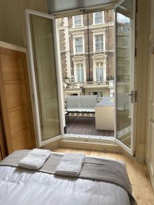 a bed in a room with a large window at Newly refurbished- Awesome very central flat in famous Notting Hill with a balcony in London
