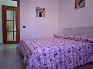 a bedroom with a purple comforter on a bed at Dimora La Genuina in Guspini