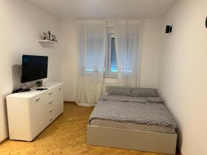 Un dormitorio blanco con una cama y un televisor. en Studio Apartman Centar 2, en Livno