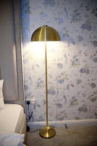 a lamp in a bedroom with a wall with flowers at Thirlmere in Upholland +12 photos