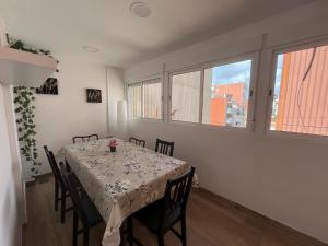 ein Esszimmer mit Tisch und Stühlen und Fenstern in der Unterkunft Apartment 4 rooms Fira Barcelona in Hospitalet de Llobregat + 14 Fotos