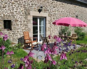 a patio with a table and an umbrella and flowers at Le Jardin des Papillons, gîte et chambre d'hôtes à Saint Fraimbault in Saint-Fraimbault