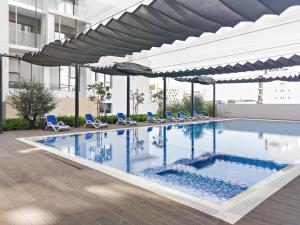 a swimming pool with chairs and umbrellas in a building at Bright Boho Loft near Yas F1 Circuit & Airport in Abu Dhabi