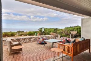 a patio with a table and chairs and the ocean at Lady Serenity - unwind in the hot tub in Kleinmond