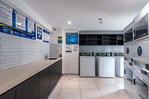 a large kitchen with white appliances and white tiles at Perricholi Central Apartments by Geko in Lima