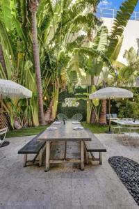 a picnic table and benches in a courtyard with palm trees at Pool and Jacuzzi. Walk to beach, South Point Pier in Miami Beach