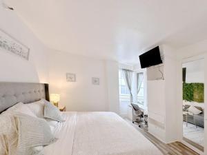 a white bedroom with a bed and a flat screen tv at Pool and Jacuzzi. Walk to beach, South Point Pier in Miami Beach