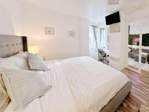 a white bedroom with a bed and a television at Pool and Jacuzzi. Walk to beach, South Point Pier in Miami Beach +18 photos