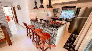 a kitchen with a counter with chairs and a stove at Casa na Praia na Ponta da Ilha in Cacha Pregos
