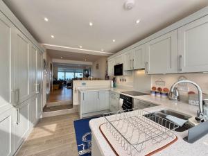 eine große Küche mit weißen Schränken und einem Waschbecken in der Unterkunft Goodwinds 4 bedroom beachside house in Torcross
